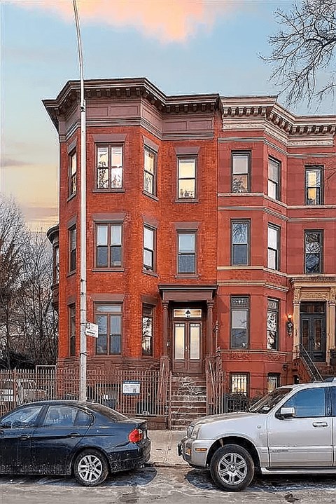 Two cars parked in front of a red brick building.