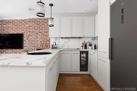 A kitchen with a brick wall and white cabinets.