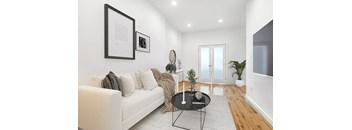 A living room with a white couch, a coffee table, and a mirror.