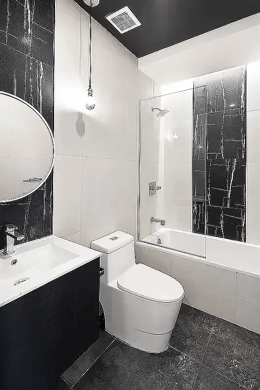 A black and white bathroom with a toilet, sink, and shower.