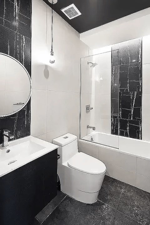 A black and white bathroom with a toilet, sink, and shower.