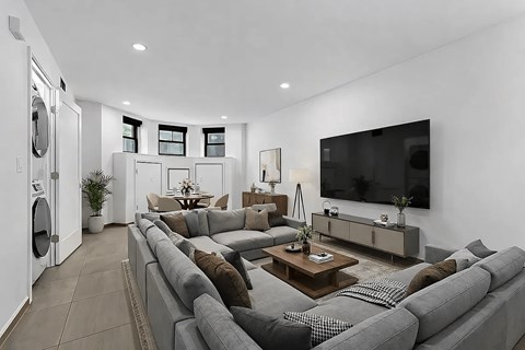 A modern living room with a grey sofa set and a flat screen TV mounted on the wall.