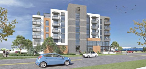 A blue car is parked in front of a modern apartment building.