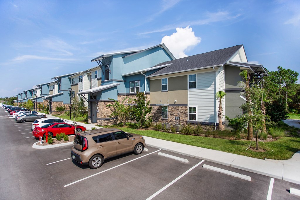 a row of apartment buildings with cars parked in front of them