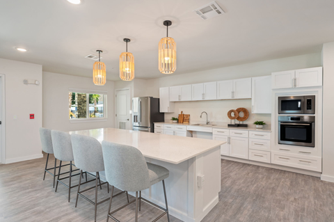 A modern kitchen with a large island and grey chairs.