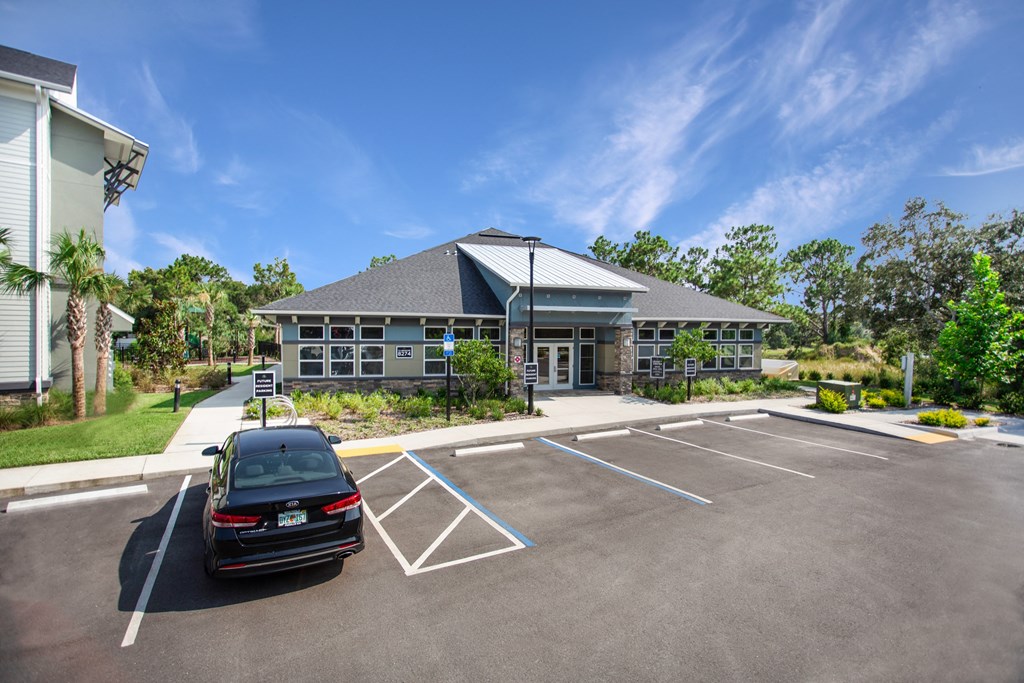A black car is parked in a parking lot in front of a building.