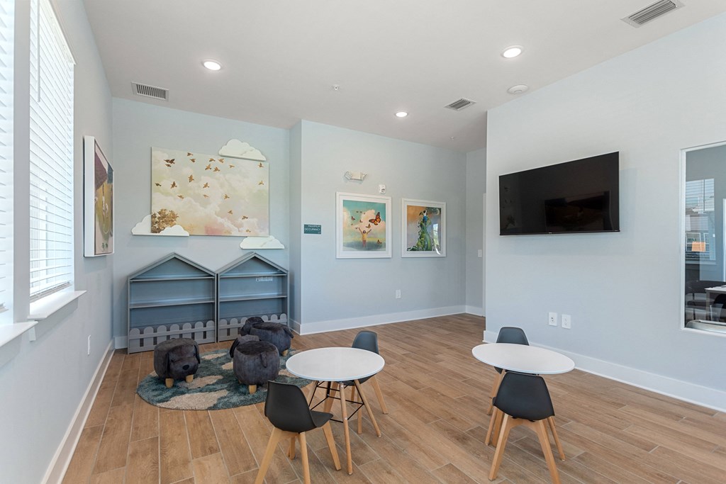 a living room with tables and chairs and a tv on the wall