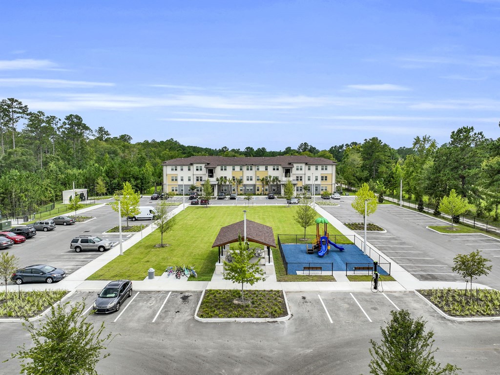 an aerial view of a parking lot and a building with a lawn