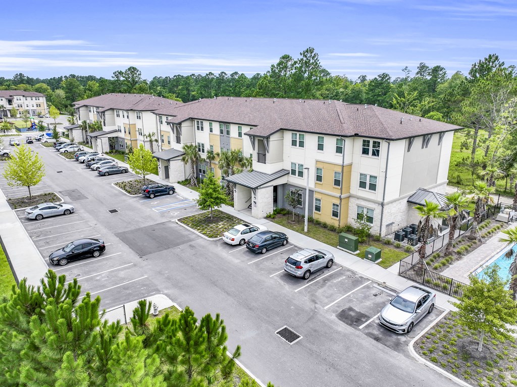 an aerial view of an apartment complex with cars parked in a parking lot