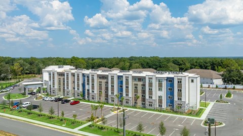 A large multi-story building with a parking lot in front.
