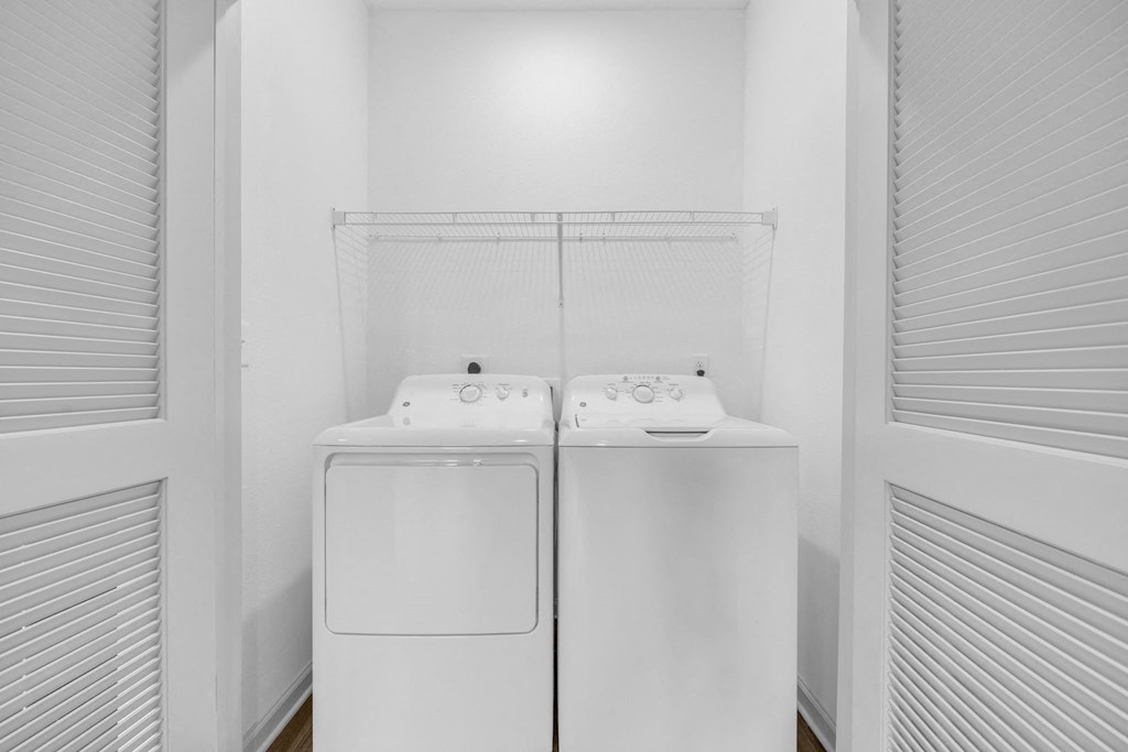 a washer and dryer in a white laundry room with white blinds
