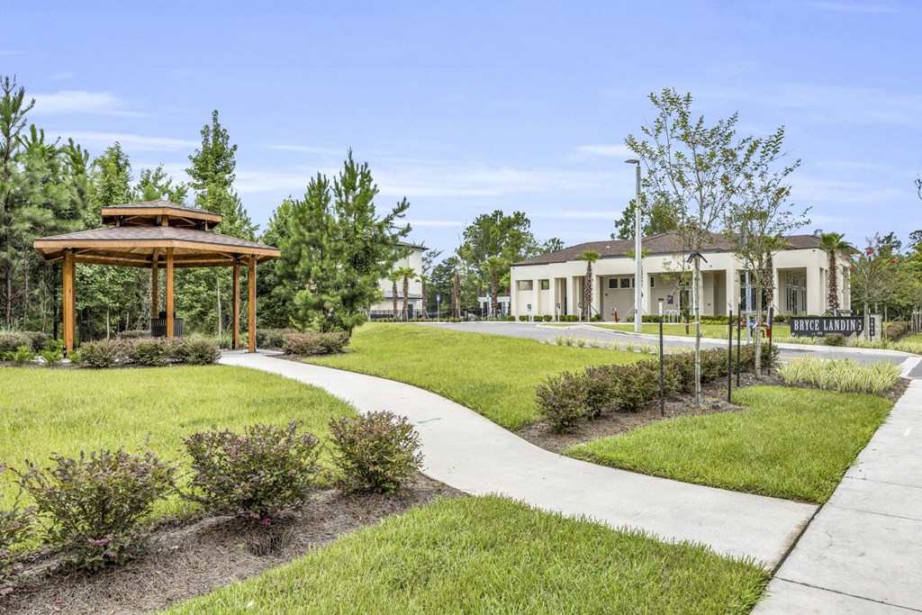 a pathway through a park with a gazebo and building in the background