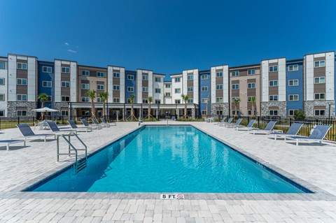 A swimming pool in front of a row of apartment buildings.