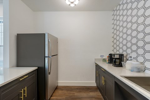 a kitchen with black cabinets and a stainless steel refrigerator