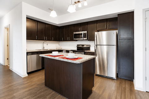 A kitchen with dark brown cabinets and a stainless steel refrigerator.