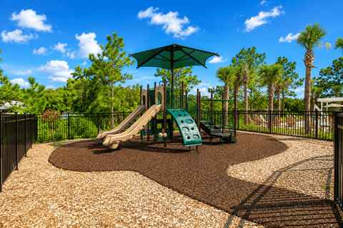 A playground with a green slide and a brown gravel area.