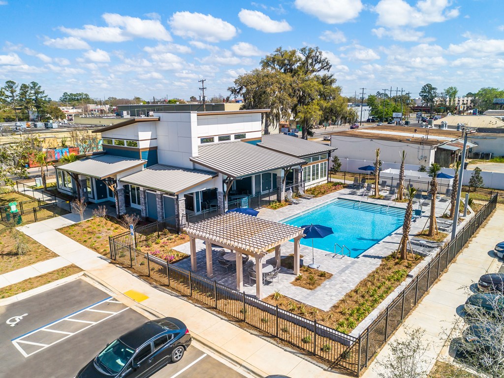 an aerial view of a building with a pool in the foreground and a parking lot in the