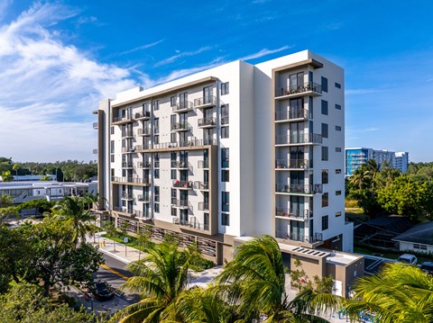 A modern apartment building with balconies and surrounded by greenery.
