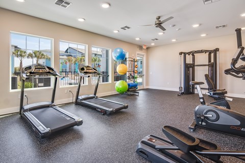 A gym with treadmills, elliptical machines, and a weight machine.
