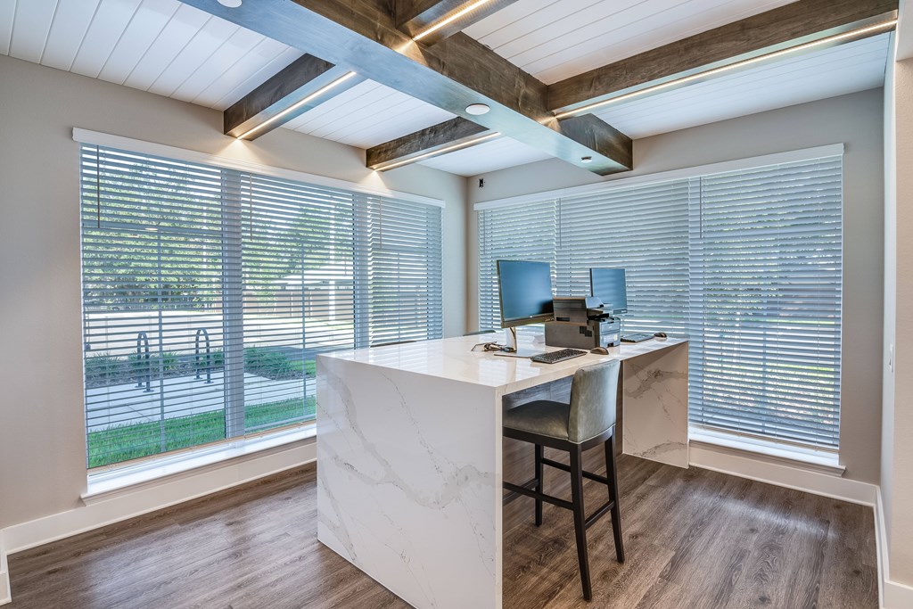 A home office with a desk and chair, a computer, and a window with blinds.