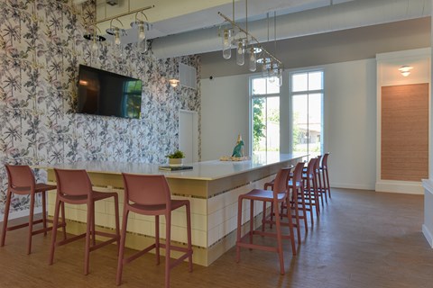 a kitchen with a bar and chairs in front of a wall with a floral wallpaper