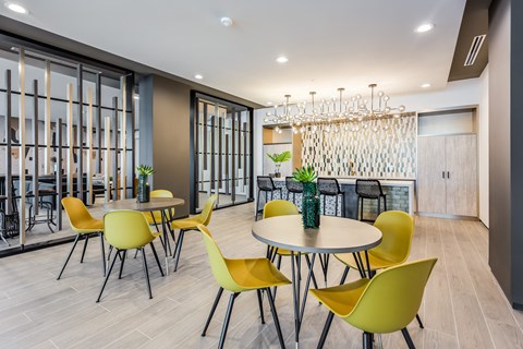 a dining room with yellow chairs and tables and a chandelier