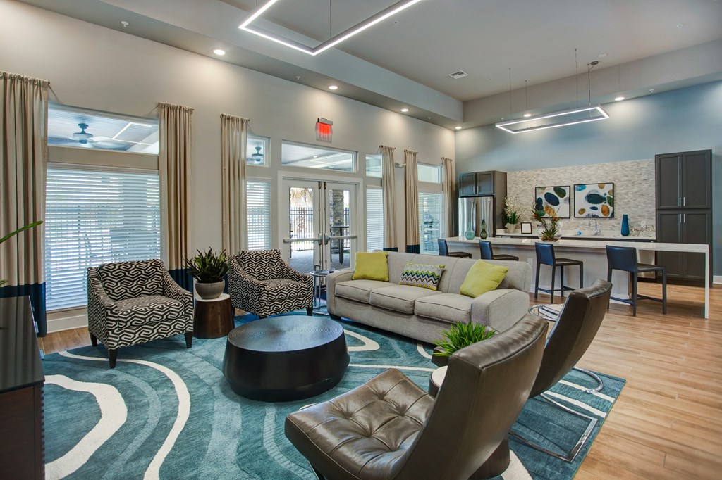 a resident clubhouse with couches chairs and a kitchenette
