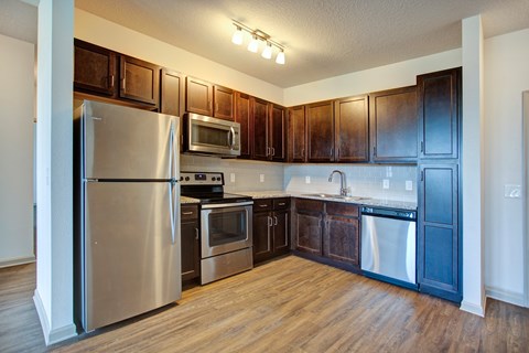 A kitchen with dark wood cabinets and stainless steel appliances.