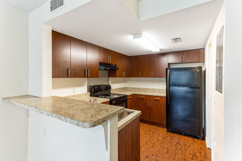 a kitchen with brown cabinets and a black refrigerator