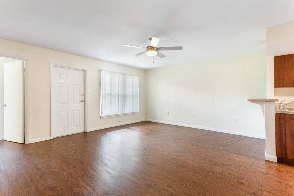 an empty living room with a ceiling fan