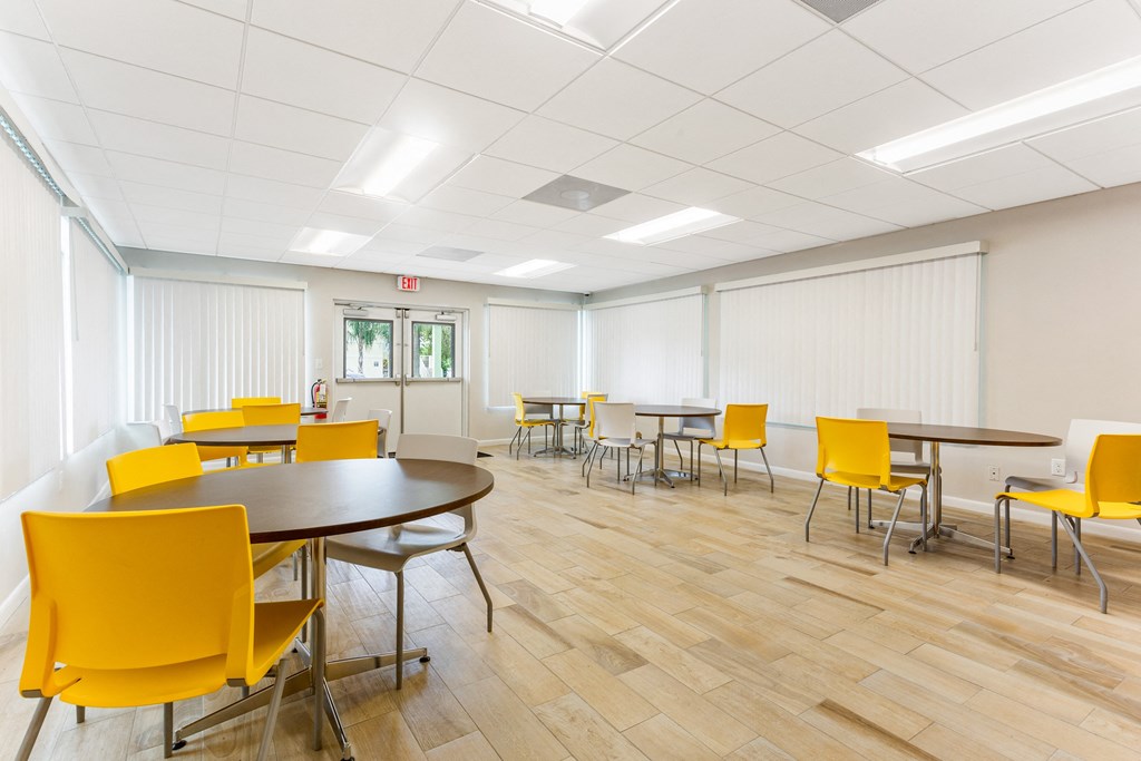 a room with white walls and yellow chairs and tables