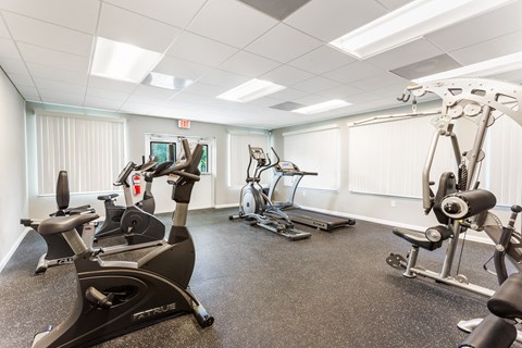 A gym with a variety of exercise equipment including a stationary bike, a rowing machine, and a treadmill.