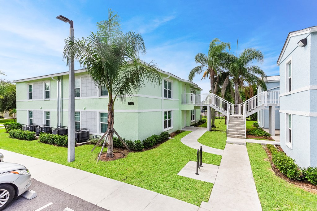 a building with a staircase and palm trees in front of it