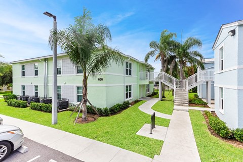 a building with a staircase and palm trees in front of it