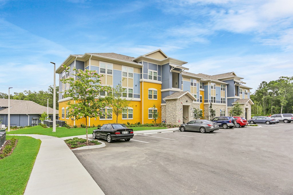 a large apartment building with cars parked in a parking lot