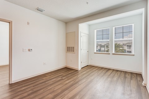 an empty living room with wood floors and a window