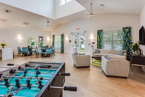 A foosball table is in the middle of a room with a couch, chairs, and a television.