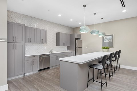 A modern kitchen with a large island and grey cabinets.