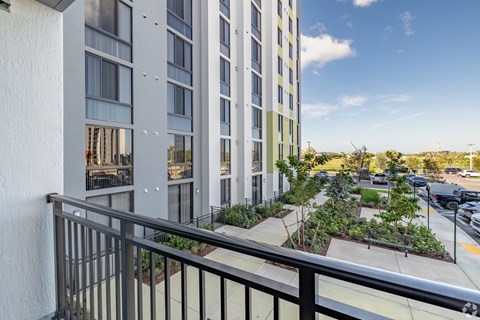A balcony overlooks a parking lot and a building with a green roof.