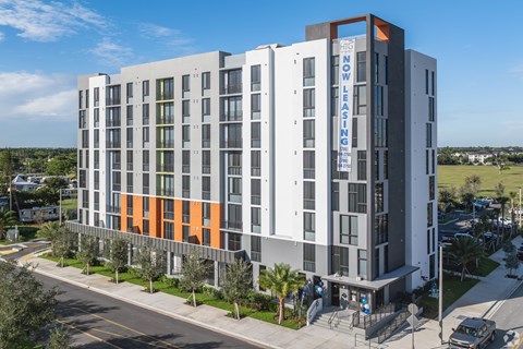 A modern multi-story building with a sign that reads "NOW LOW LEASING".