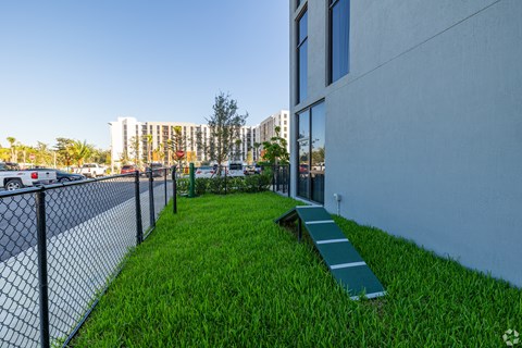 A grassy area with a bench and a fence in front of a building.