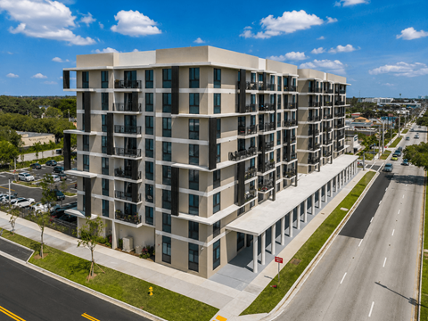 A modern apartment building with a parking lot in front.