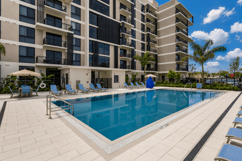 A large swimming pool in front of a multi-story apartment building.