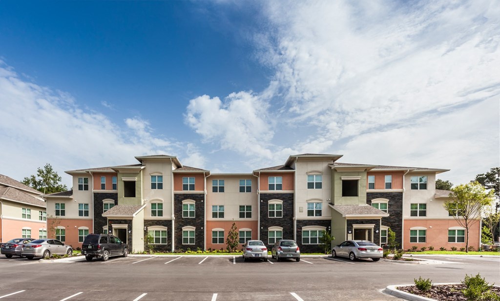 a parking lot with cars in front of an apartment building