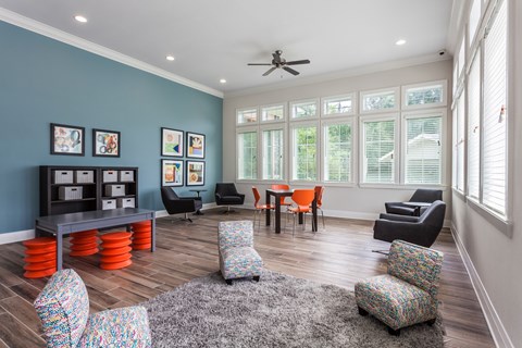 A living room with a grey rug and a ceiling fan.