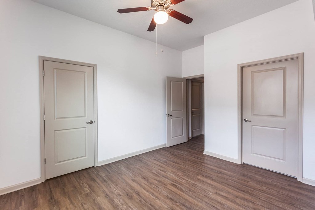 an empty living room with white walls and a ceiling fan