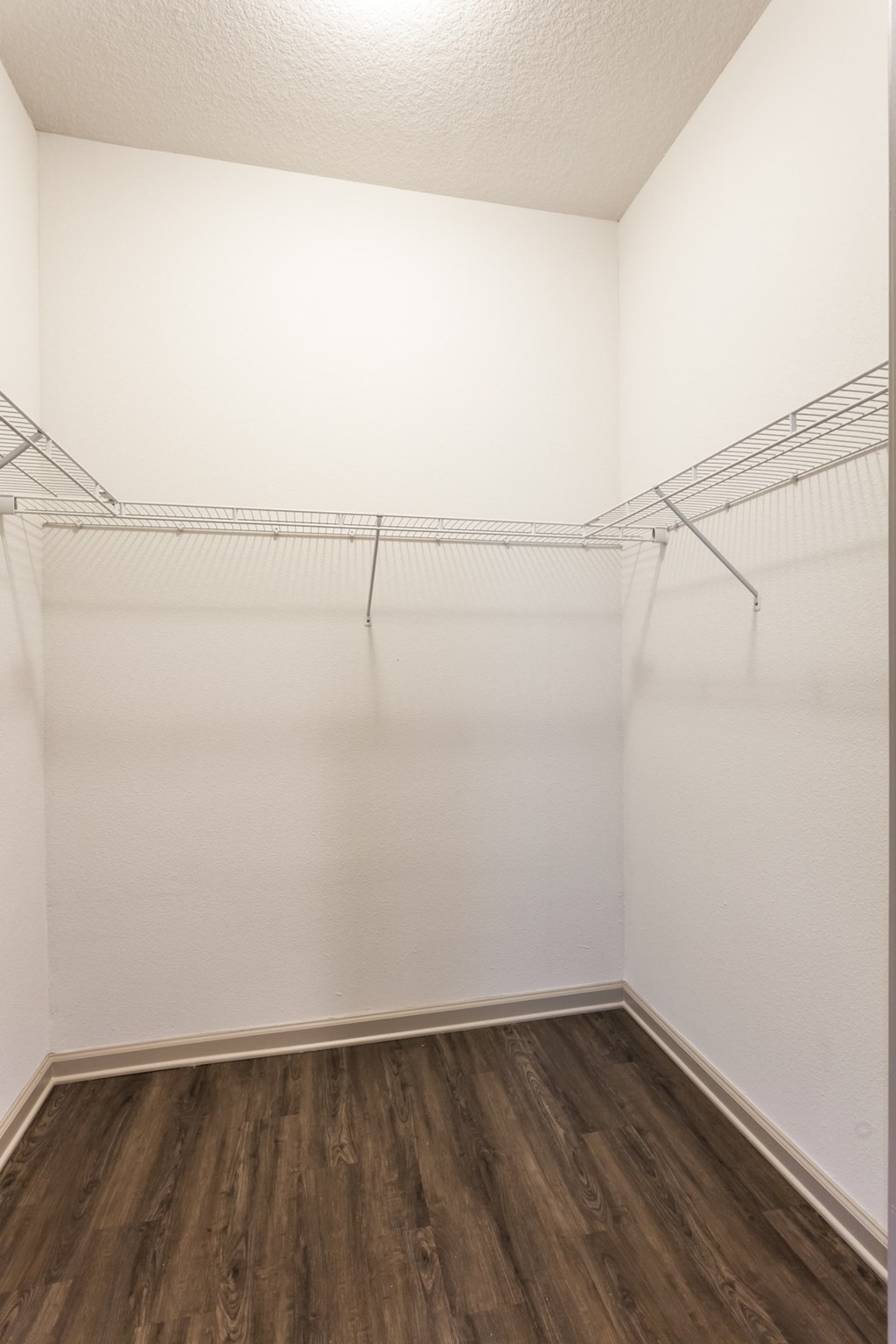 an empty bedroom with white walls and wood flooring and a closet