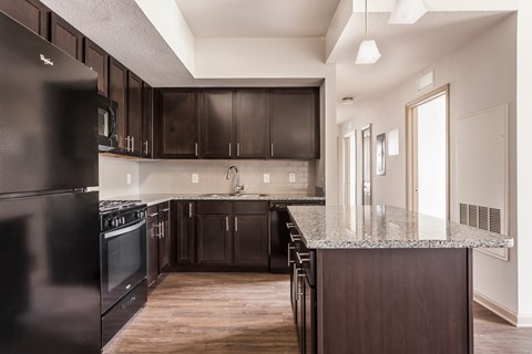 A kitchen with dark wood cabinets and a black refrigerator.