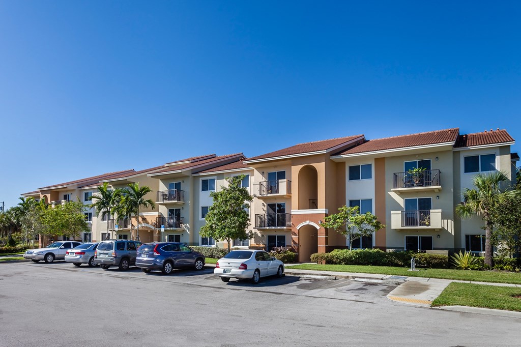 a row of apartment buildings with cars parked in front of them