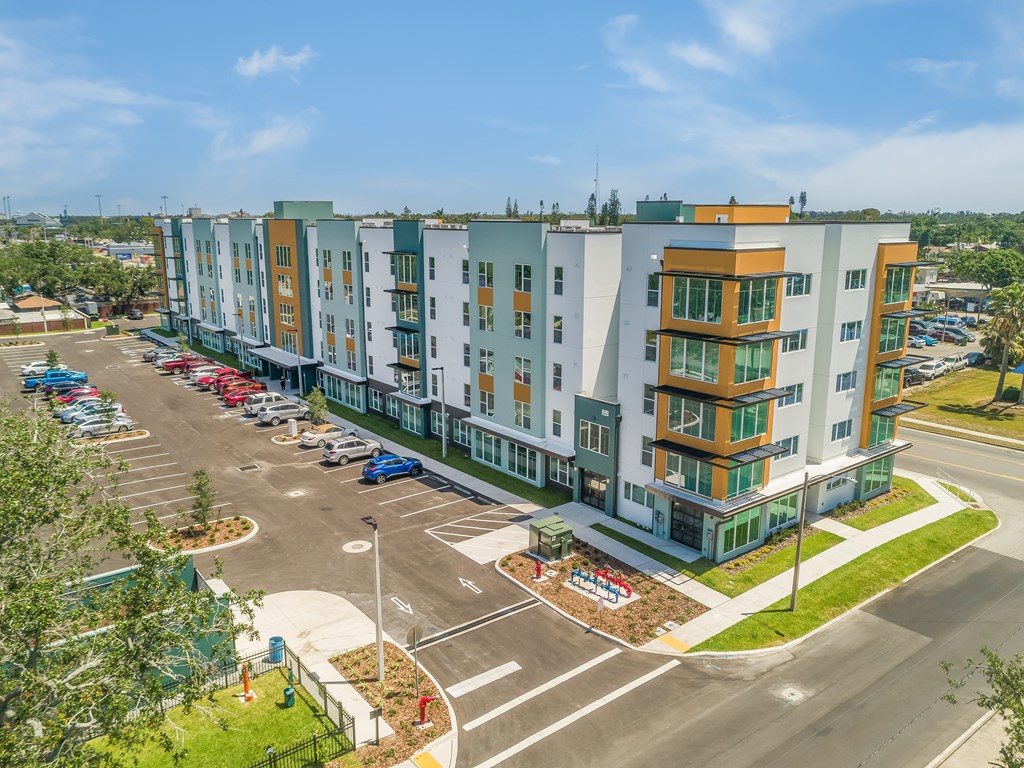 A large apartment complex with a parking lot in front.